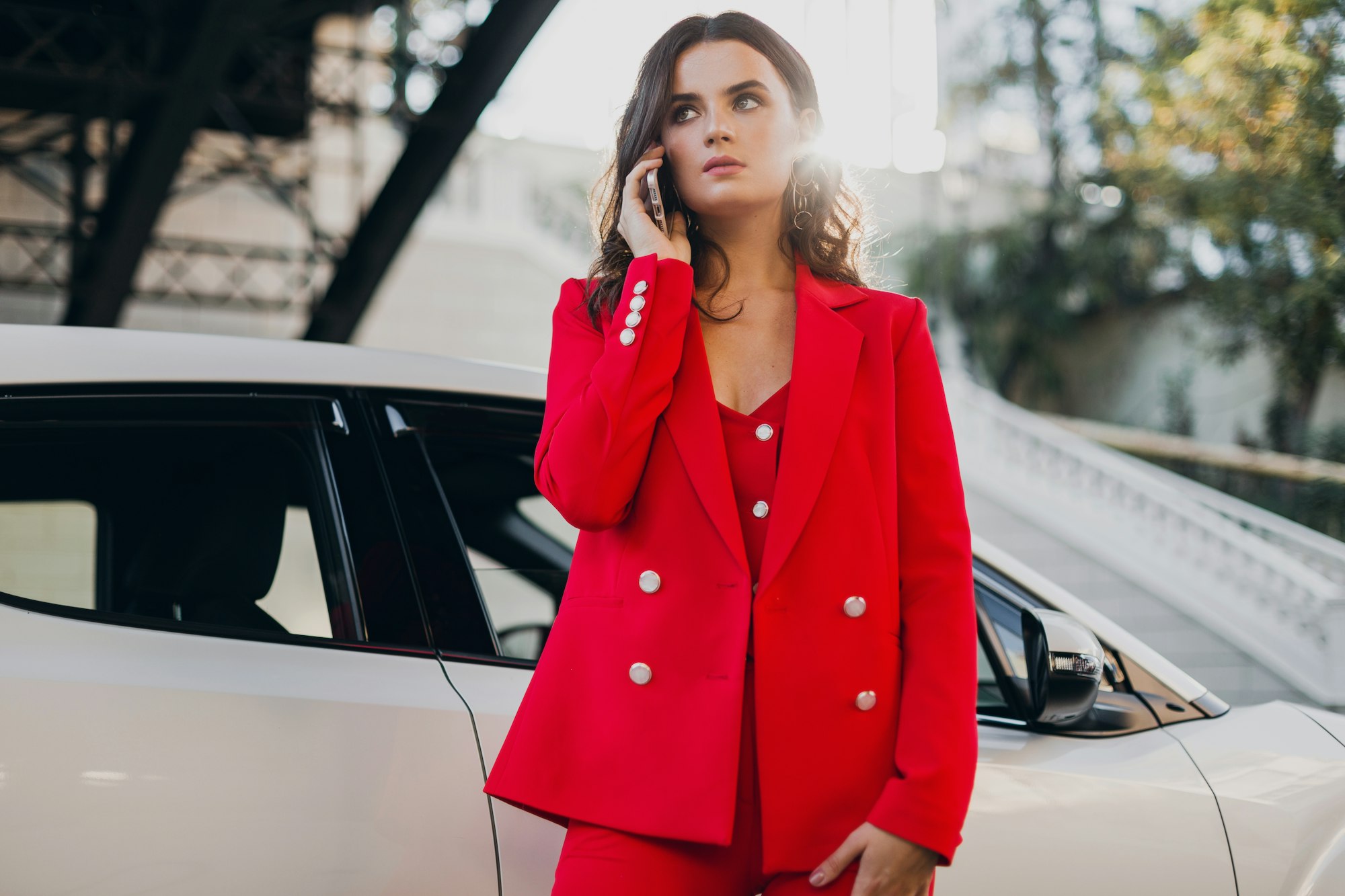 belle femme sexy en robe rouge posant dans une voiture en train de parler affaires au téléphone