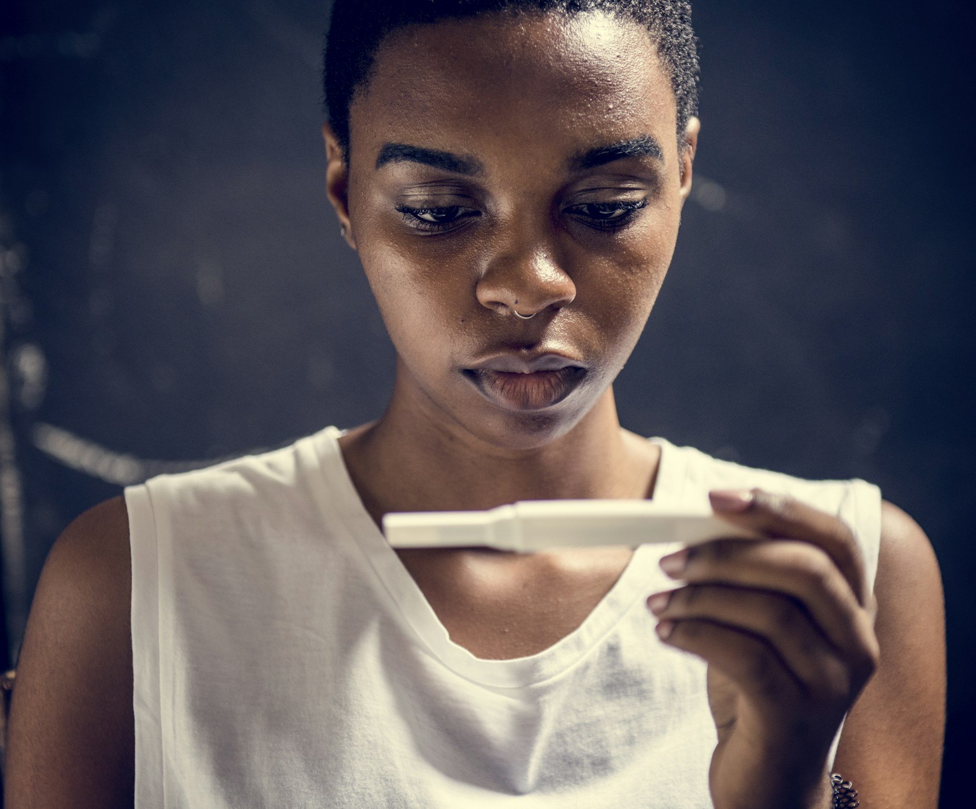 Gros plan d'une femme noire avec un test de grossesse dans la main.