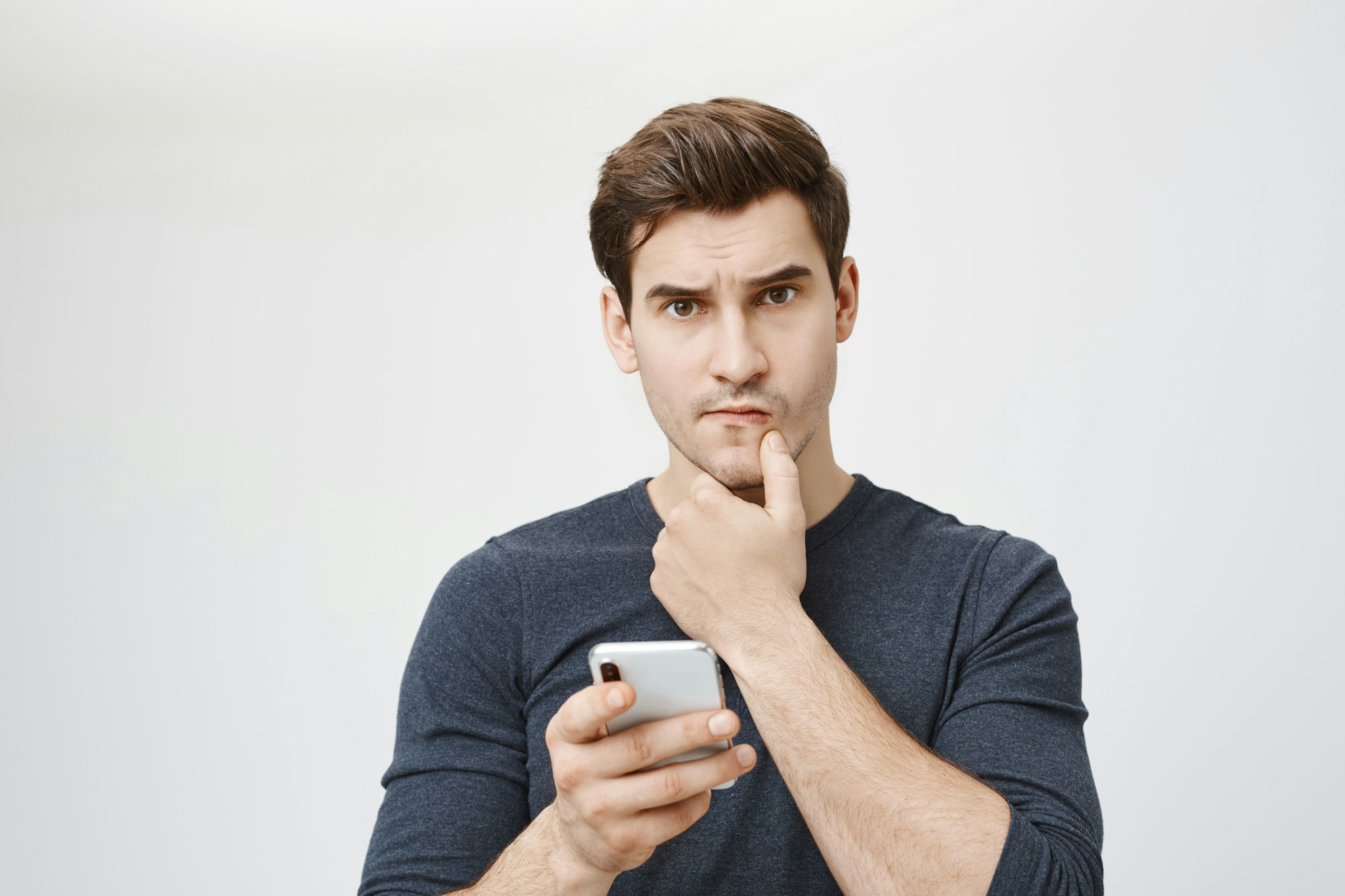 Une photo en médaillon d'un jeune étudiant blanc qui a l'air inquiet et confus alors qu'il tient un smartphone à la main et qu'il a l'air de ne pas savoir où il en est.