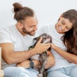 positive-young-diverse-couple-stroking-their-dog-in-new-home.jpg