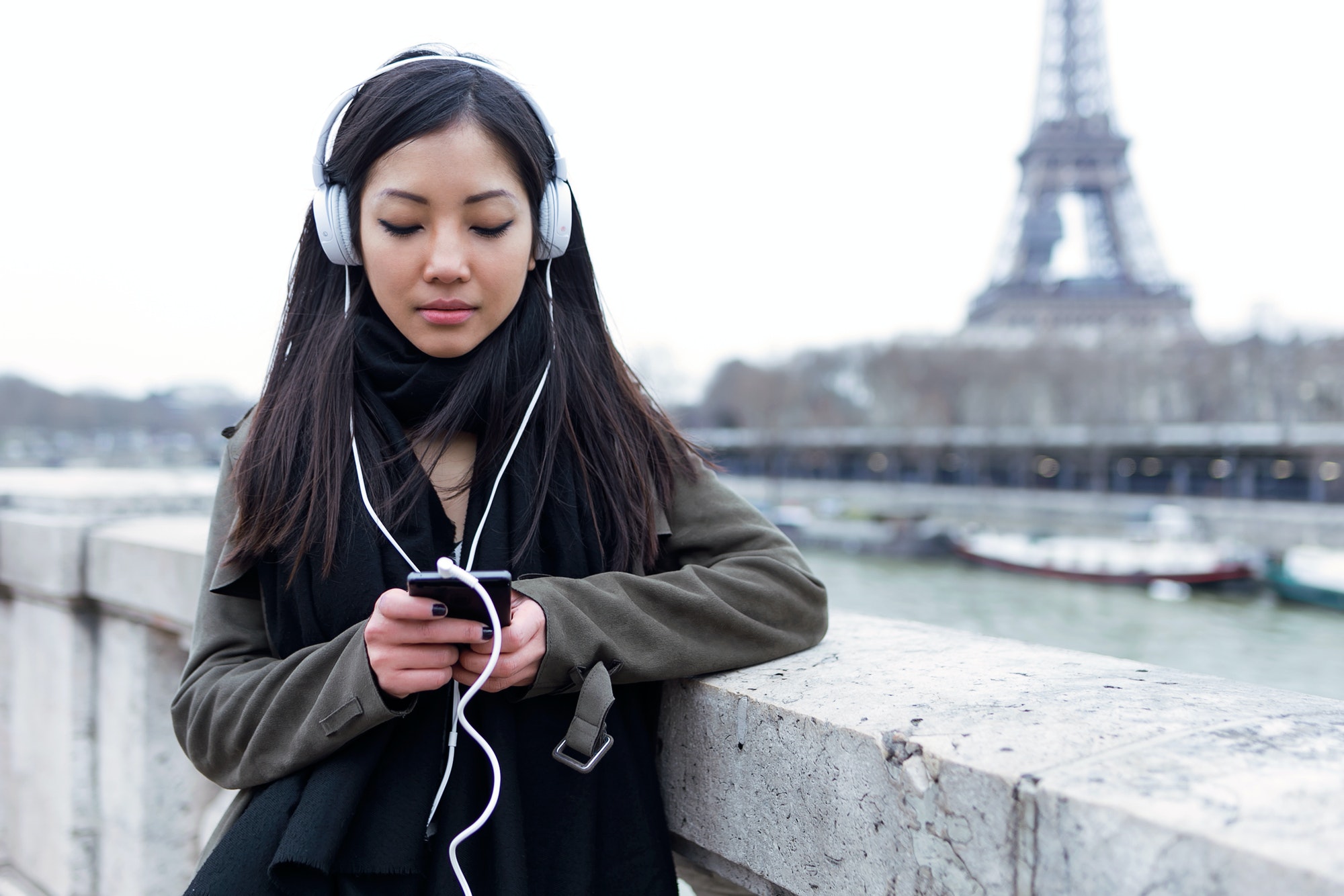 Belle jeune femme asiatique écoutant de la musique avec un téléphone portable à la main