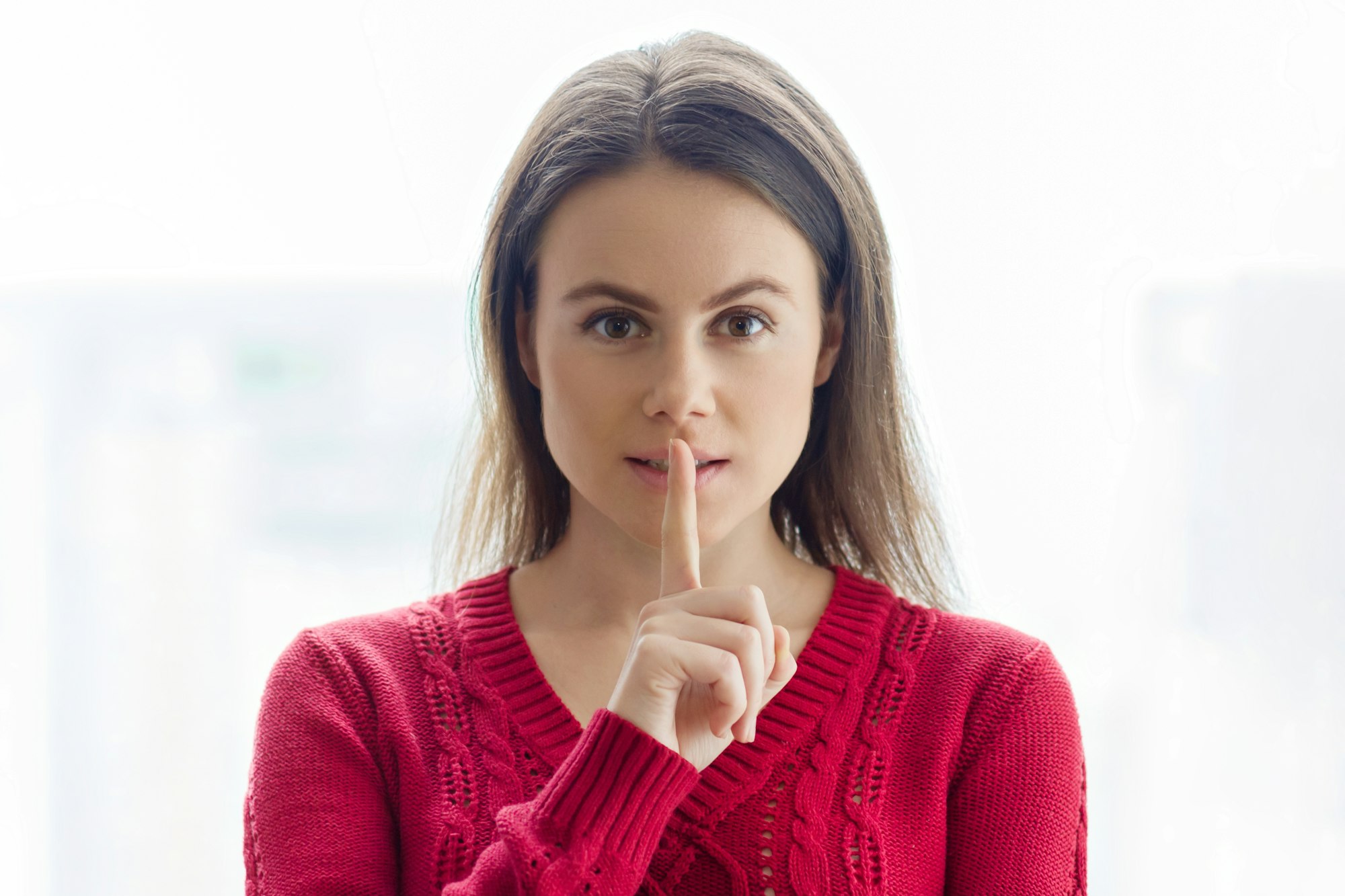 Signe secret, une jeune femme montre le signe du silence avec un doigt sur les lèvres