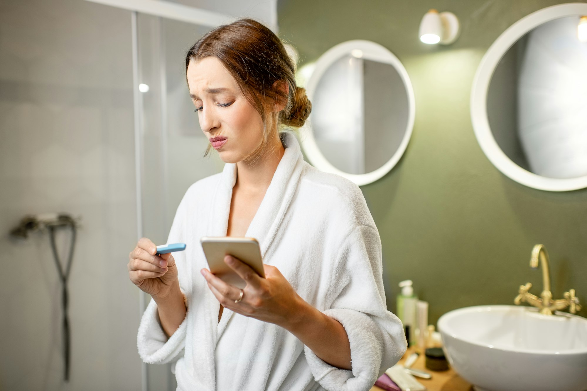 Femme inquiète avec un test de grossesse dans la salle de bain