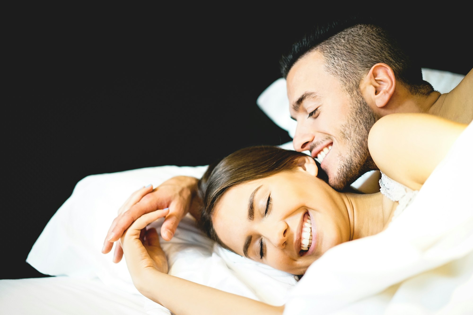 Jeune couple sexy et amoureux allongé sur le lit pendant leur lune de miel