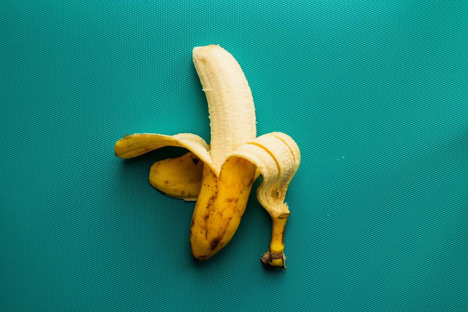 une banane pelée posée sur une surface bleue