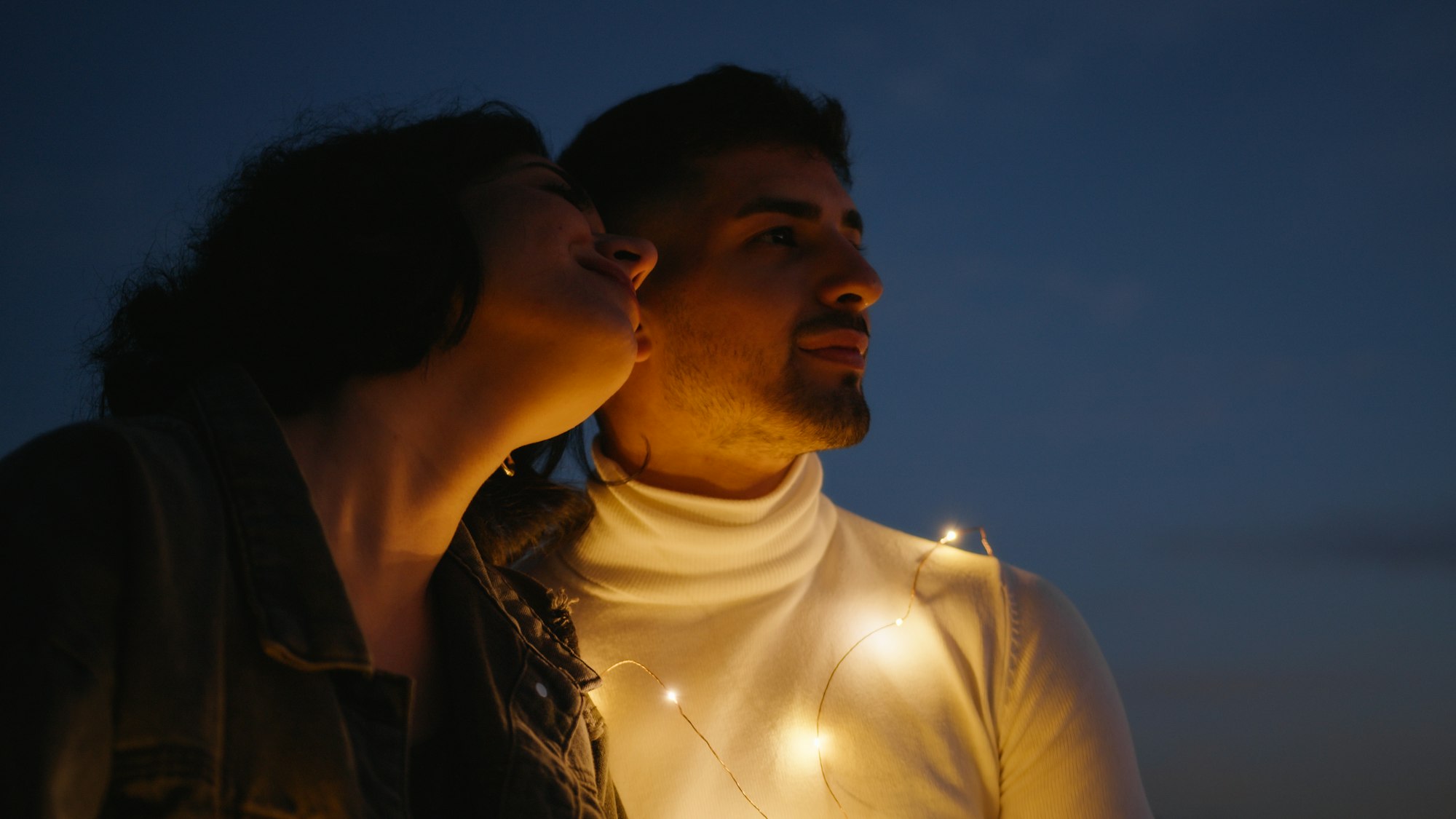 Couple s'embrassant la nuit à l'extérieur avec des lumières allumées