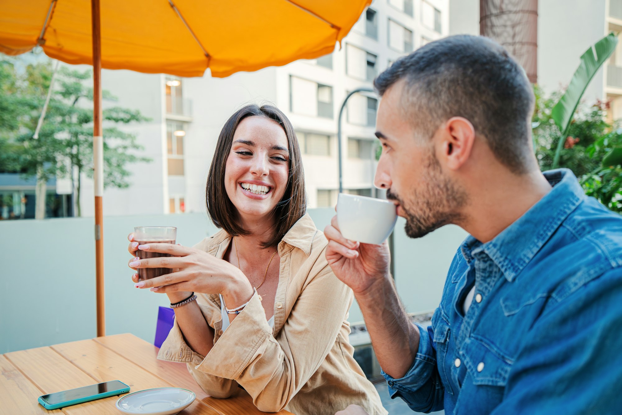Un jeune couple blanc heureux fait une pause après avoir fait ses courses à la terrasse d'un café.