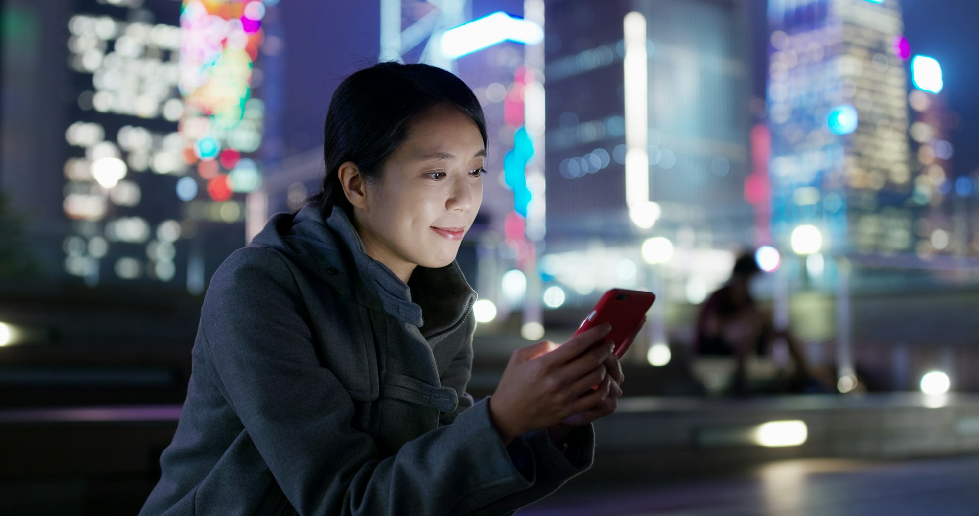 Une femme utilise son téléphone portable en ligne la nuit