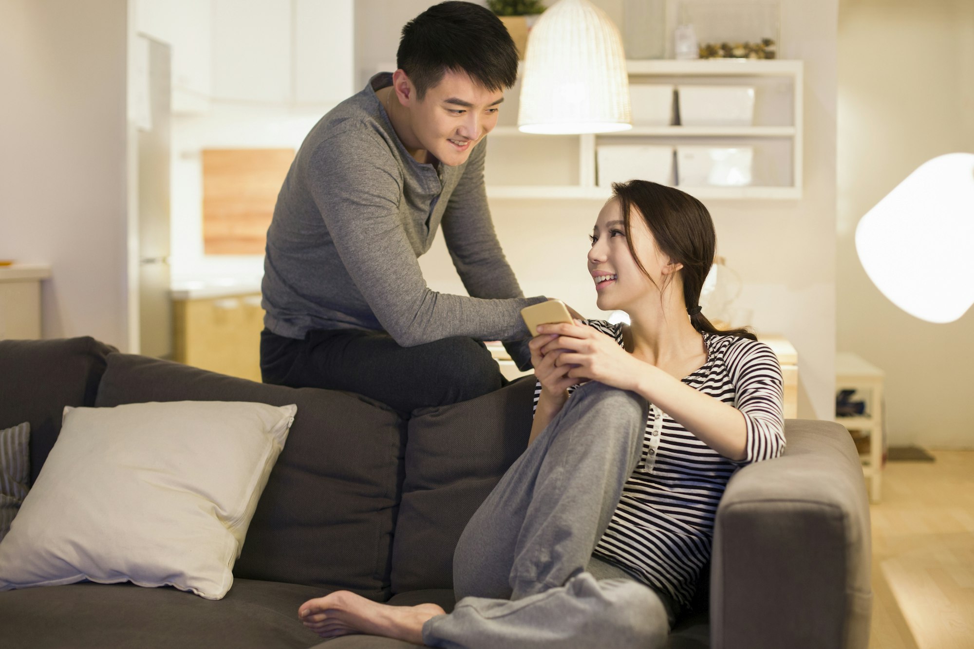 Un jeune couple utilise un smartphone sur le canapé du salon.