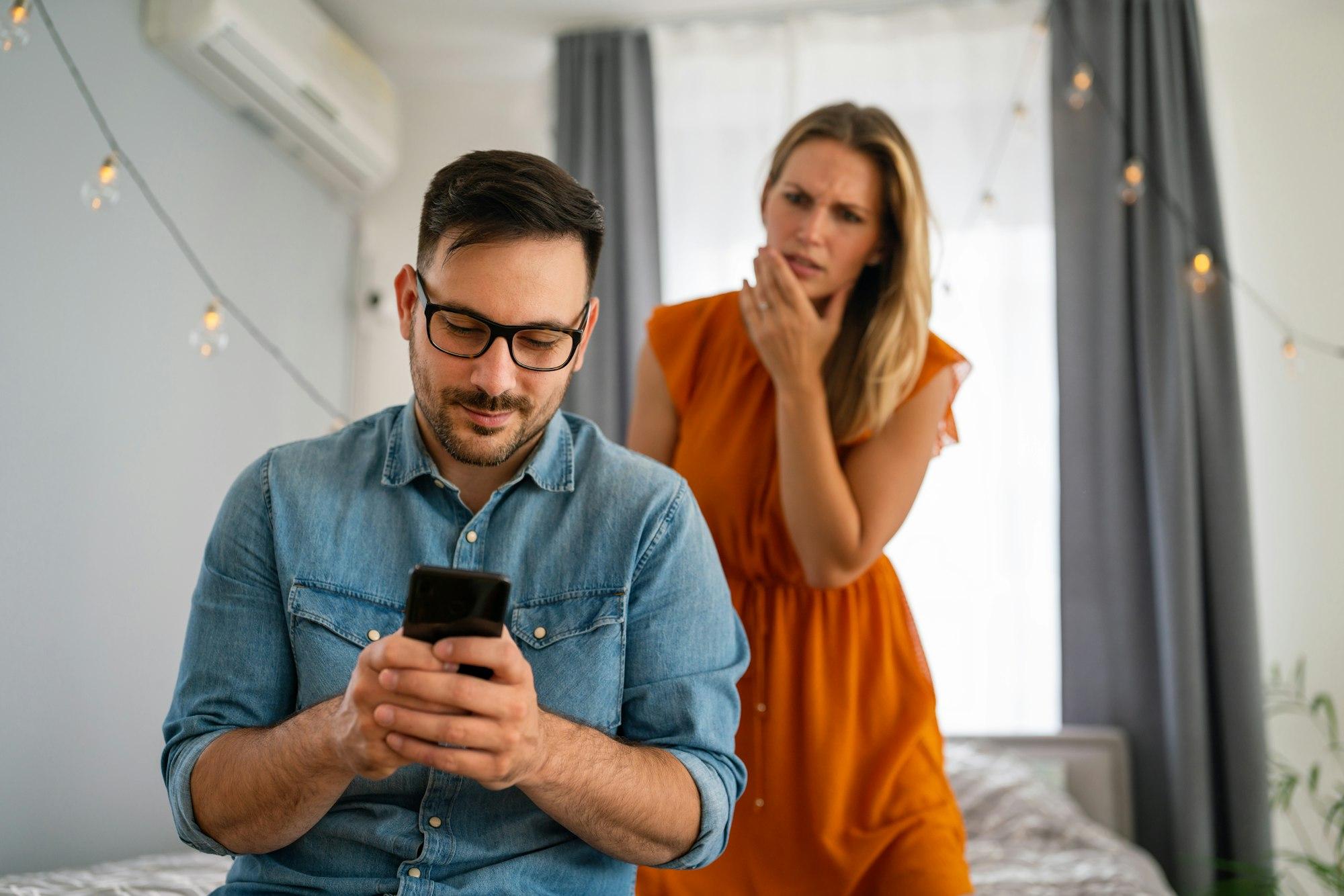 Une femme jalouse espionne son petit ami et surveille son téléphone portable. Concept de couple trompé par la jalousie