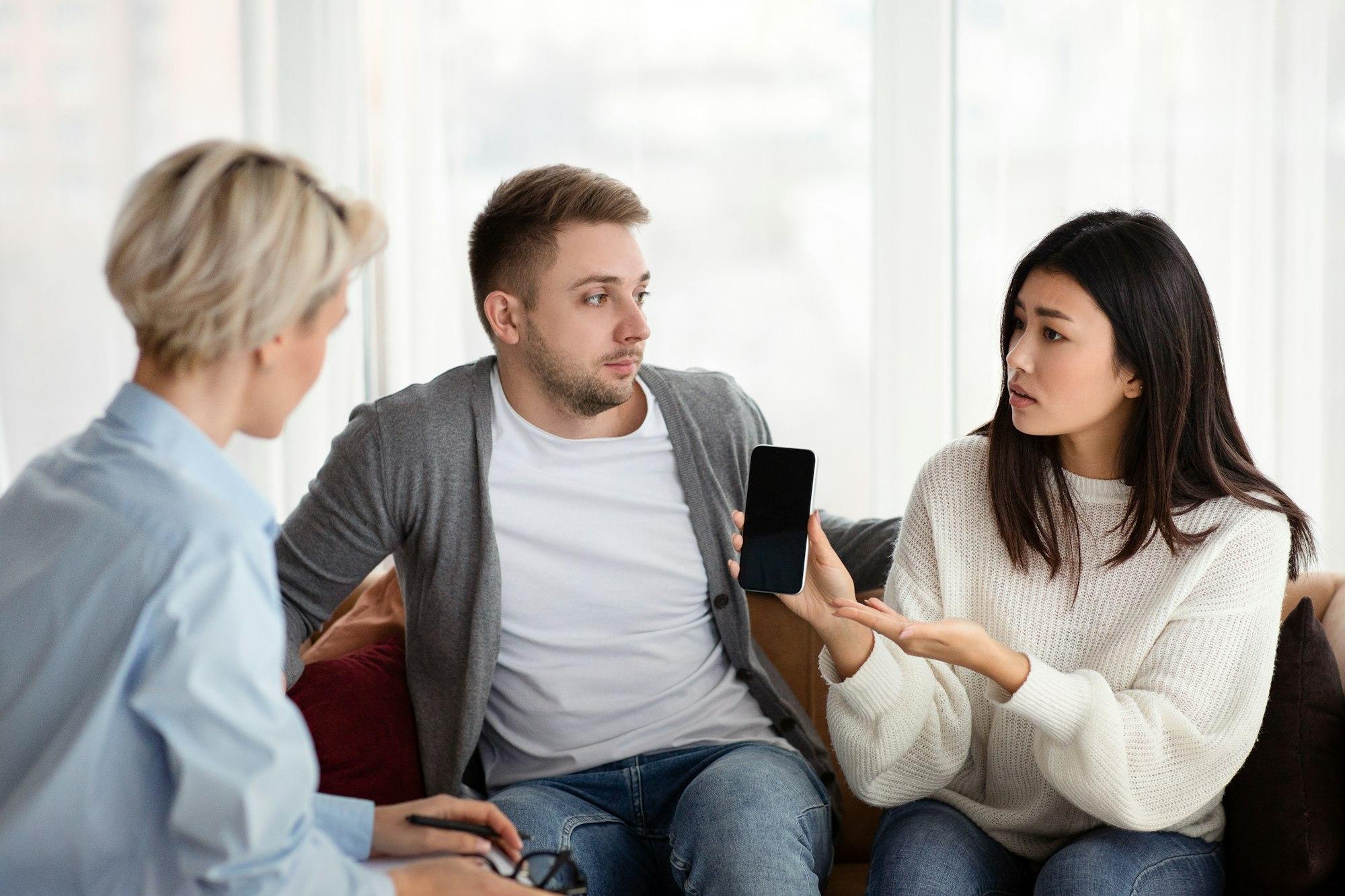 Une femme semble tromper son mari avec son téléphone portable pendant une séance de thérapie au bureau