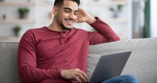 Happy arab guy using laptop, chatting on dating website