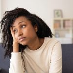 Worried woman thinking about her problems while sitting on a sofa at home
