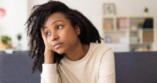 Worried woman thinking about her problems while sitting on a sofa at home