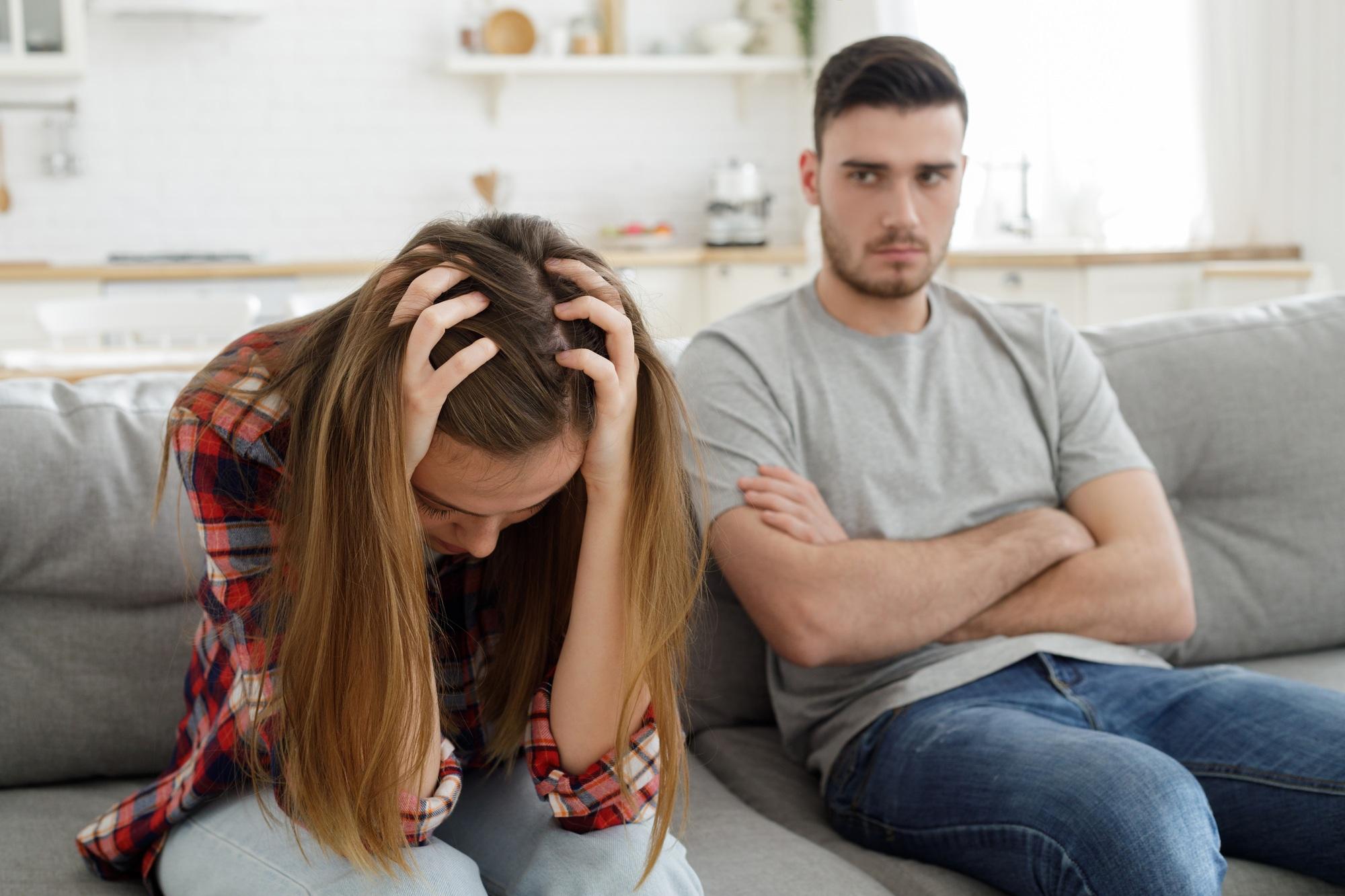 Un jeune couple agacé et chamailleur s'assoit sur le canapé à la maison après un gros accident