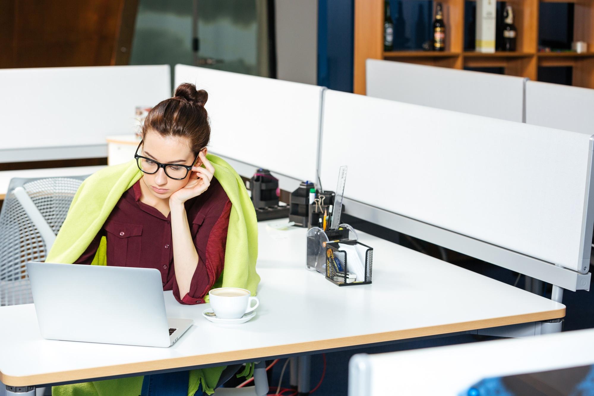 Une femme d'affaires travaillant avec un ordinateur portable a froid au bureau.