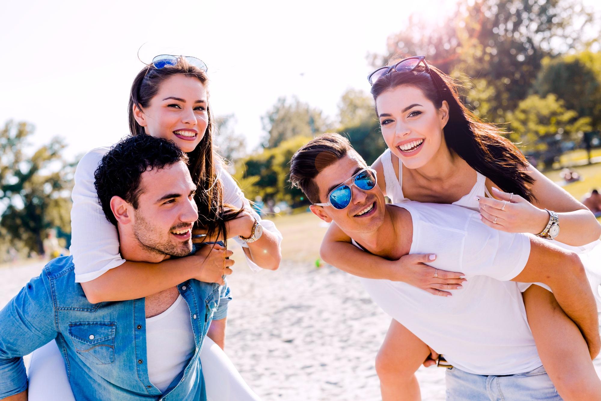Un groupe de jeunes gens heureux portant des femmes sur une plage de sable.