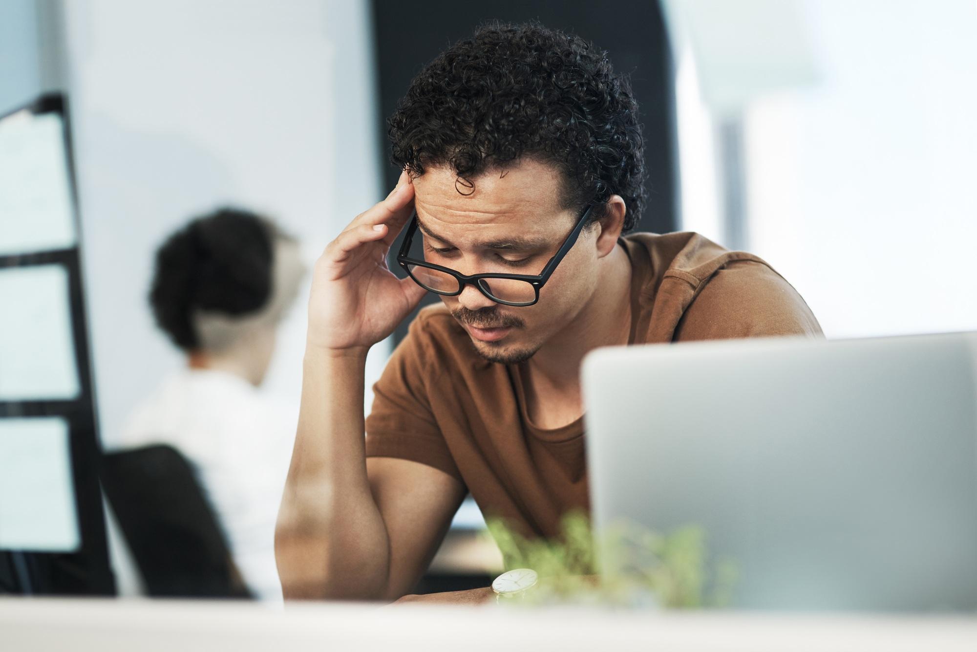 Photo d'un jeune et bel homme d'affaires assis dans son bureau et stressé.