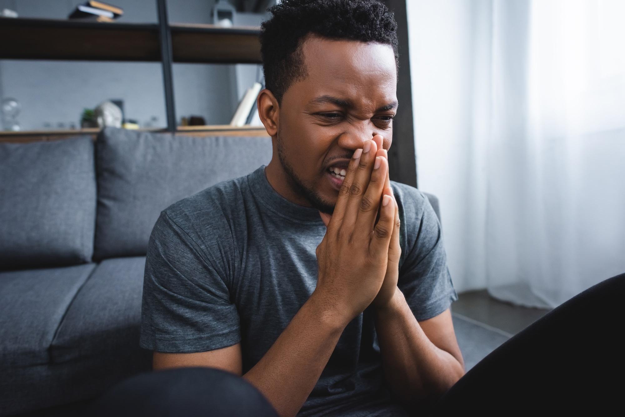 Un Afro-Américain stressé, les mains jointes, souffre d'une crise de panique à son domicile