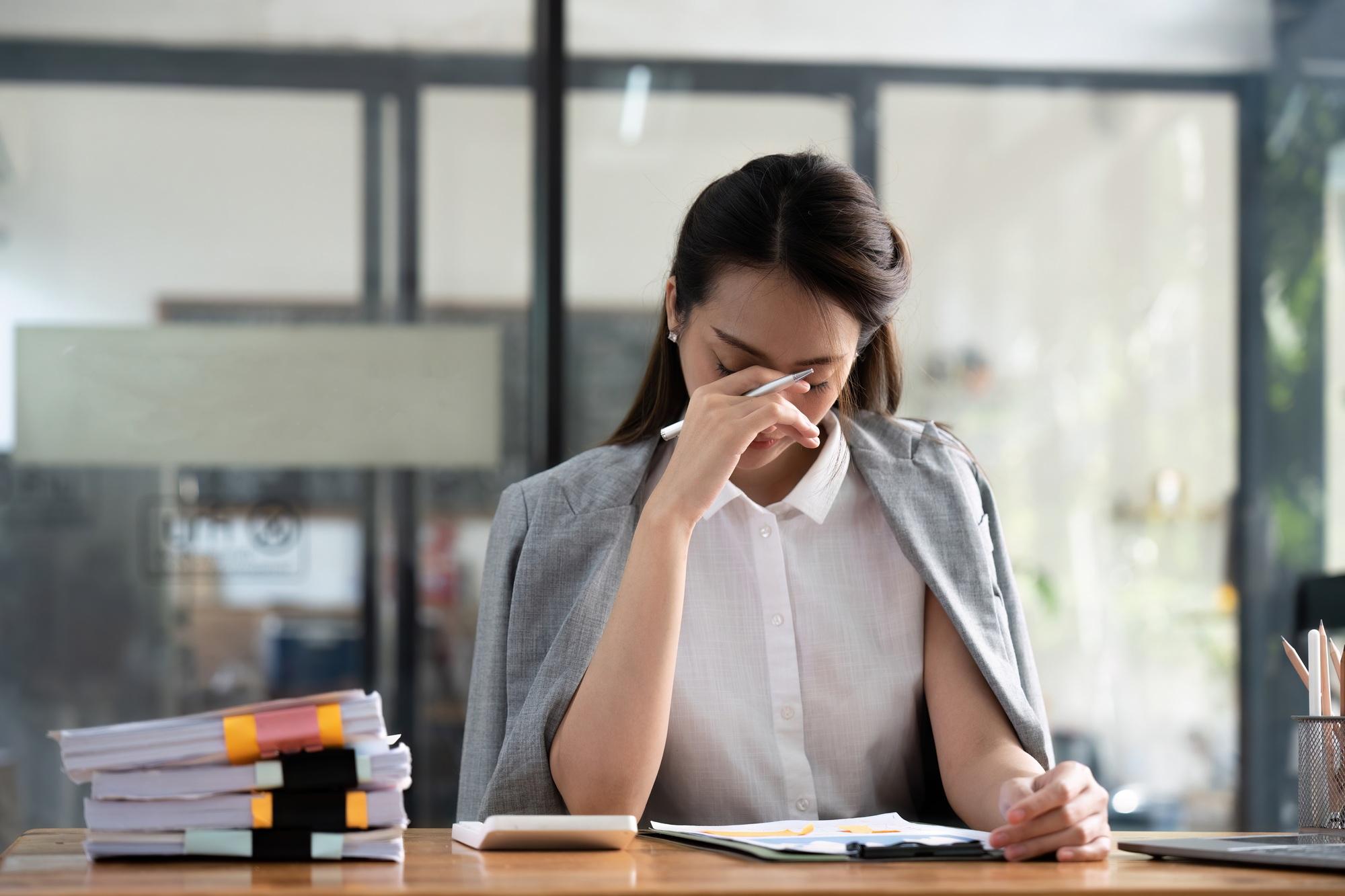 Une femme d'affaires stressée qui travaille chez elle sur un ordinateur portable et qui a l'air inquiète, fatiguée et dépassée.