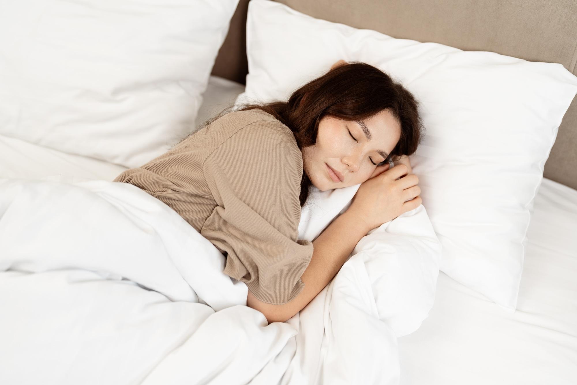 Jeune femme dormant paisiblement dans un lit blanc douillet