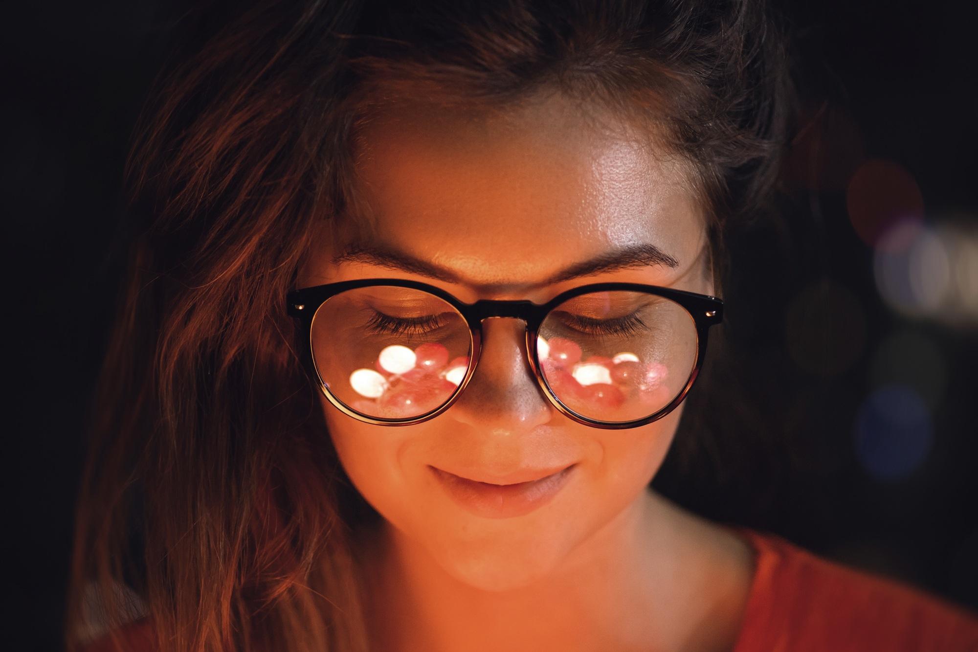 Une jeune femme avec des boules de lumière qui se reflètent dans ses lunettes...